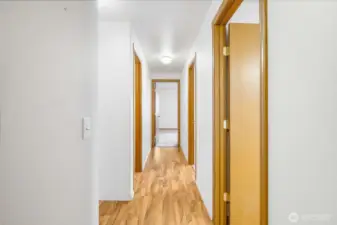 With your back to the laundry room, we see two bedrooms on the right, the primary at the end of the hall, and the main bathroom to the left.