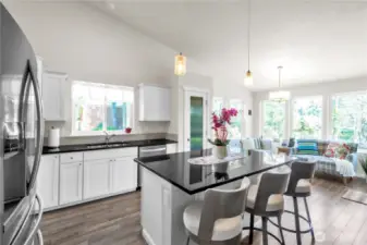 Large kitchen with granite counters, tile backsplash, stainless steel appliances, pantry, and breakfast island.