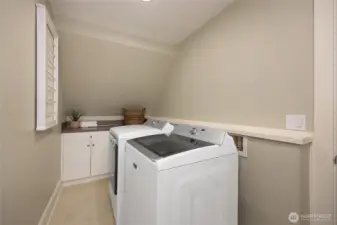 Convenient upper-level laundry room with storage and folding area.