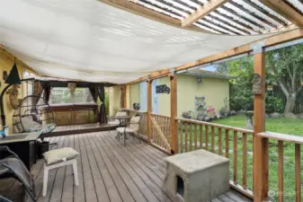 Covered deck with hot tub and access to the garage.