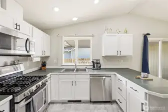 Light and bright kitchen featuring freshly painted cabinets with new hardware pulls, stainless steel appliances, gas stove, and microwave—offering a clean, updated look and great functionality for everyday cooking.