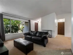 The living room is spacious with a massive window looking out to the front yard. Vaulted ceilings add to the expansiveness of this space.