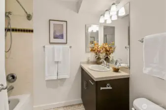 Nice bathroom with tub and stone tile counters.