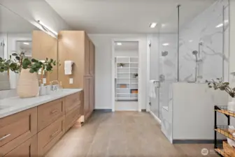 Modern and bright primary en-suite bathroom with neutral tones, double integrated sink vanity, ample drawer storage, enclosed glass shower with built-in bench.