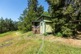 Separate Tiny Home/Studio has a front deck and inside a bath, loft and kitchenette with small locked storage on side. There is a separate easement driveway to the studio.