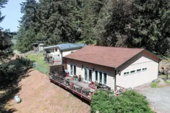 Bunkhouse has French doors to private deck. Main house has a metal roof and deck, with an enclosed sunroom that is heated and air conditioned. Main house has a fenced yard. Tiny Home/Studio shown past the main house.