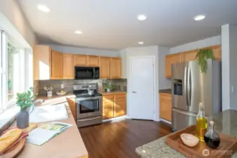 Spacious kitchen designed for easy meal preparation, with an archway that seamlessly connects to the dining and living areas. The kitchen showcases a nearly full-length window that frames beautiful backyard and greenbelt views, filling the space with abundant natural light.