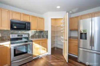 The kitchen features a stunning tiled backsplash, stainless steel appliances, and a convenient walk-in pantry—perfect for both style and functionality.