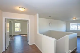 The upper-level landing welcomes you with elegant double doors opening into the expansive primary suite, while a spacious loft area sits to the right.