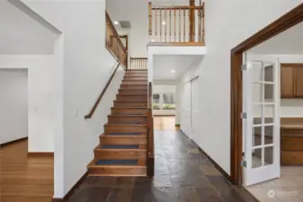 Beautiful entry is bright and open with vaulted ceilings, slate floor, and shining wood staircase.