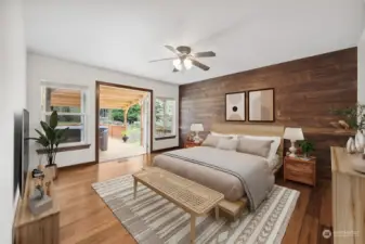 Primary bedroom is a private oasis with French doors leading to covered deck and hot tub. Beautiful rustic wood accent wall gives this room a warm and cozy feel. (Photo digitally staged)