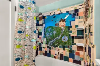 This whimsical and one-of-a-kind tile shower is a true work of art! Featuring a vibrant mosaic mural, it showcases a charming cottage scene with a winding stone path, colorful flowers, trees, birds and more.