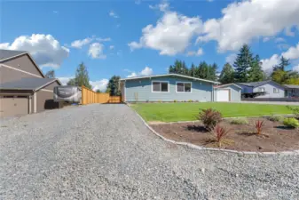 The gravel driveway leads to more parking in your fenced back yard.