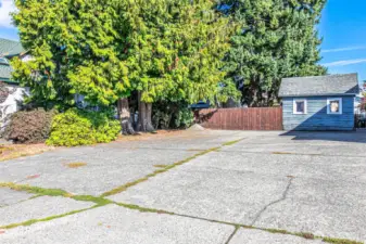 Paved parking area and blue shed are a part of the vacant lot.