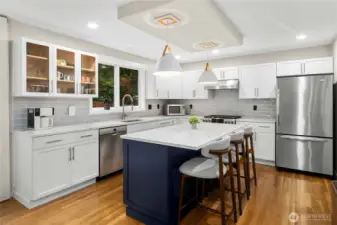 Spacious kitchen with large center island, quartz counters, tile backsplash and stainless steel appliances.
