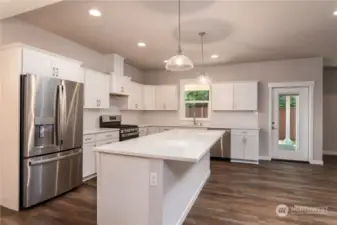 Kitchen does not include white cabinets or a fridge.  It does include quartz counters, a gas range, micro hood and dishwasher.  This is a spacious kitchen with a large island.