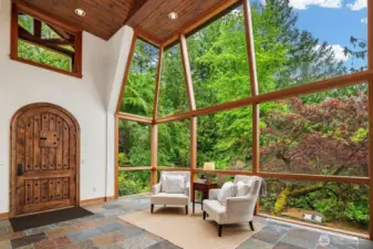 2-story covered exterior portico with custom arched wood and iron front door. Wood plank ceiling.