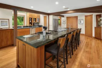 Kitchen has extra-long prep island with bar seating, 4-burner gas cooktop with grill