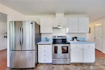 Kitchen features new flooring, freshly painted cabinets, and new cabinet hardware.