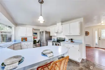 Kitchen with breakfast bar, looking towards living room and front entrance.
