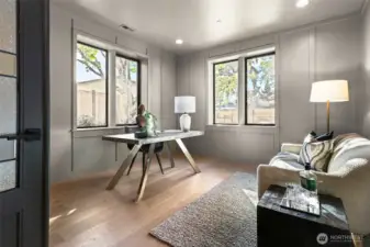 Color-drenched office wrapped in custom millwork where the walls and ceiling are a warm unified color. Wonderful outlook to the backyard. Built-in cabinetry on the left side wall behind the door. French doors with decorative glass panels.