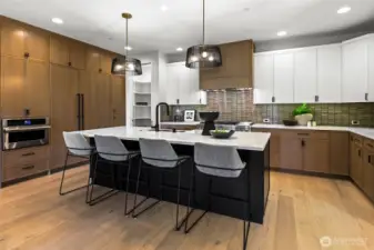 Large island with seating for four, JennAir® RISE(TM) dishwasher, full-height tile backsplash, elegant rift sawn oak cabinets. Rift sawn a special milling process that creates a uniform appearance without visible knots that are normally seen in oak. Two cutlery drawer inserts.