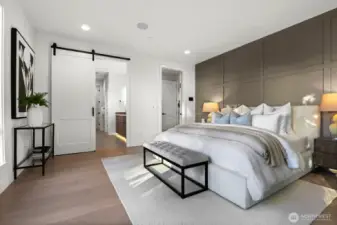Primary bedroom's barn-style sliding door leads to the primary bathroom. Two speakers installed in the bedroom and two are pre-wired in the bathroom.