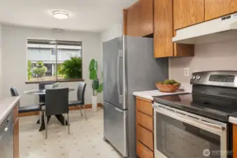 Stainless refrigerator and range surrounded by hard oak cabinetry