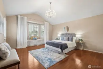 Primary bedroom with cathedral ceiling and gorgeous chandelier! What a cute window bench (that has storage)!
