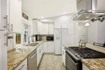 Kitchen with a modern gas range, ample prep space, sleek granite countertops and stainless steel appliances.
