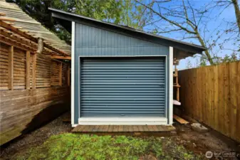 Versatile detached outbuilding with a modern roll-up door, great for a creative studio, or additional storage.