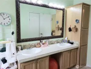 A Close up View of the 5 Piece Primary Master Bathroom Showing Tile Counter Top, Tile Floor, and 3 Door Linen Closet.
