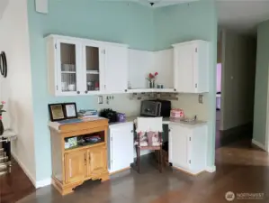 A Built In China Hutch In the Dining Room Area with White Cabinets, Tile Back Splash and  Hard Wood Flooring to Match the Kitchen.