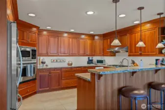 Spacious kitchen with custom cherry cabinetry, stainless appliance, granite counters.