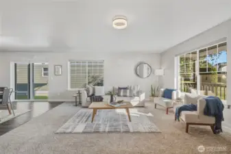 The spacious living room offers large windows on two sides for all-day sunlight, cozy carpet, and easy flow into the rest of the home.