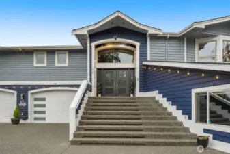 Grand front entry with elevated setting and welcoming staircase leading to the main level.