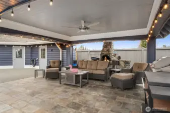 Pool side covered cabana with outdoor fireplace, ceiling fan, and comfortable seating area ideal for year-round entertaining.