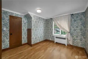 BR 2 - Vintage-inspired wallcovering, original trim, and hardwood floors give this bedroom a warm sense of character and charm.