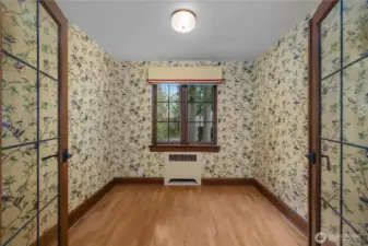 Den - Cheerful wallcovering, divided-light doors, and hardwood floors highlight the home’s distinctive historic charm.