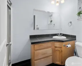 Main en suite bath with granite counter top, tile floor, and shower.