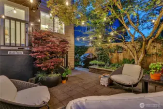 Enchanting fully fenced back yard with brick patio and retaining wall style planters.