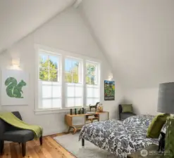 One of two light filled upstairs bedrooms under vaulted spaces. Solid wood floors grace all rooms in this home.