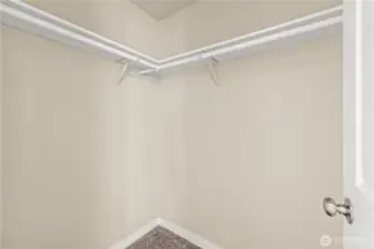 Generous walk-in closet with built-in dual hanging rods and upper shelving, offering plenty of storage for clothing and accessories. Conveniently located inside the primary suite for easy organization and functionality.