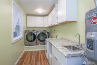 Large utility room featuring ample cabinets and a utility sink.