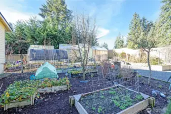 Located toward the rear, three greenhouses and raised garden beds offer an ideal gardening setup.