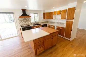 Large kitchen with tilework, butcher block island with breakfast bar, beautiful hood, and lots of storage space