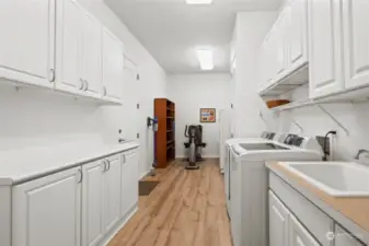 The laundry room has loads of cabinet storage with Shelf Genie pull-out systems, a utility sink and vinyl plank flooring. Plenty of space for an extra freezer, craft area or hobbies.