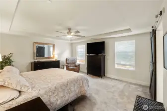 Large primary bedroom with coffered ceiling and fan.