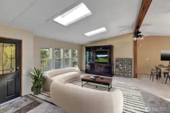 Beamed ceiling with sky lights in the open and light living room area. Room for sofas, recliners, entertainment center and more.