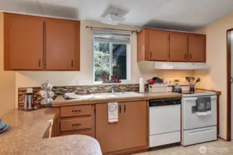 Window over the deep double sink. Plenty of prep space and storage in this kitchen. Matching white appliances for your convenience.